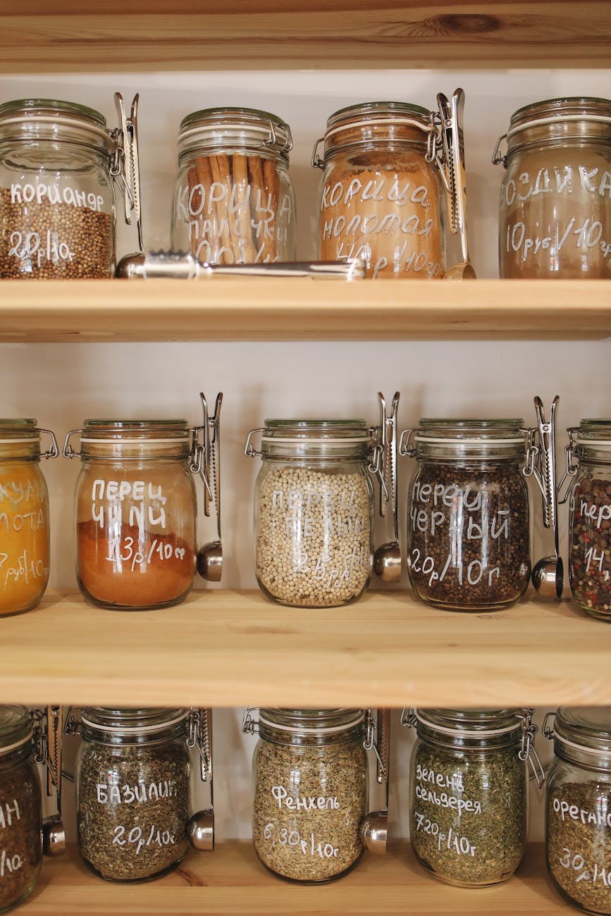 variety of spices in glass jars on wooden shelves